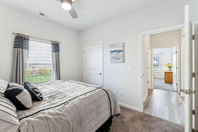 bedroom with visible vents, a ceiling fan, wood finished floors, carpet flooring, and baseboards