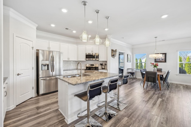 kitchen with visible vents, backsplash, ornamental molding, stainless steel appliances, and a sink