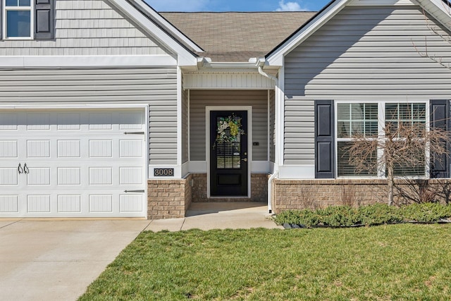 property entrance featuring concrete driveway, a yard, a garage, and roof with shingles