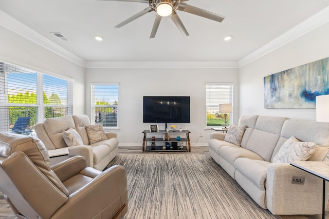living room with a wealth of natural light, visible vents, and crown molding