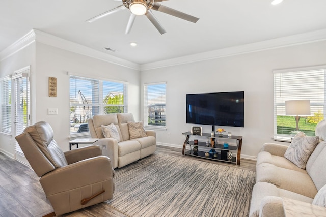 living area featuring visible vents, ornamental molding, a healthy amount of sunlight, and wood finished floors