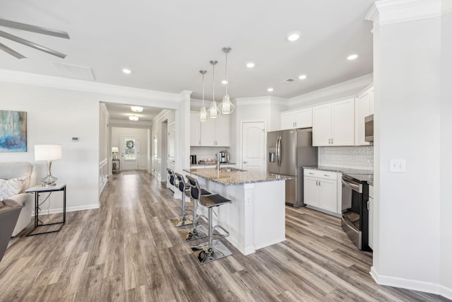 kitchen featuring a sink, white cabinets, open floor plan, appliances with stainless steel finishes, and tasteful backsplash