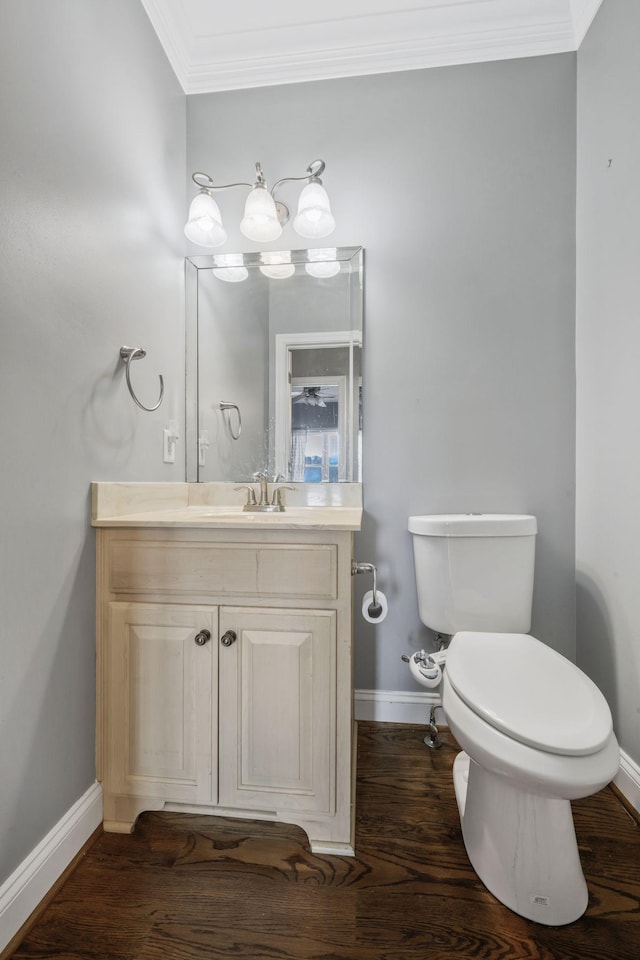 bathroom with vanity, toilet, crown molding, and wood finished floors