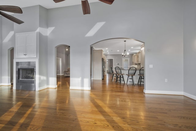 unfurnished living room with wood finished floors, baseboards, and ceiling fan