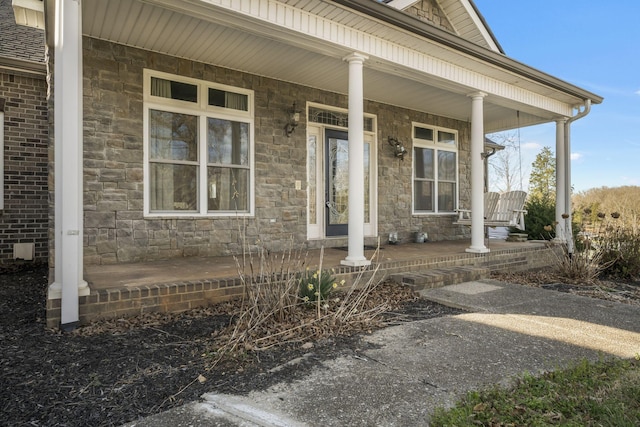 view of exterior entry with stone siding and a porch