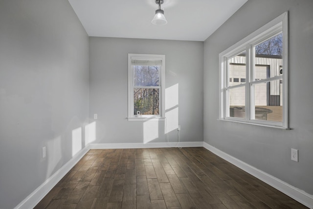 spare room with baseboards and dark wood-style flooring