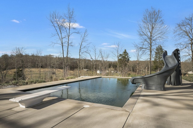 pool featuring a patio area, a diving board, and a water slide