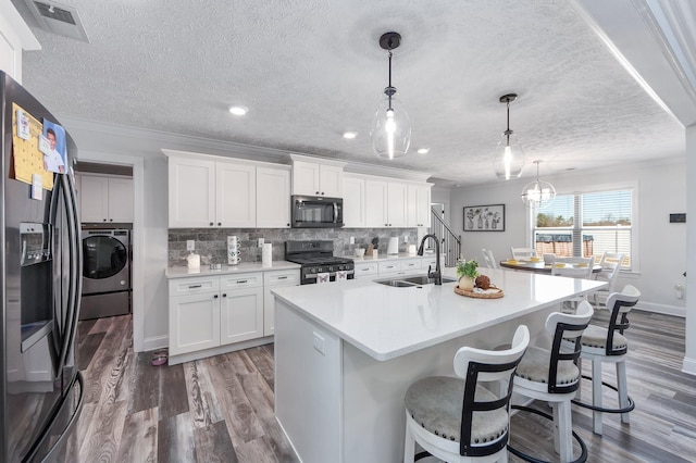 kitchen with backsplash, washer / clothes dryer, stainless steel appliances, and a sink