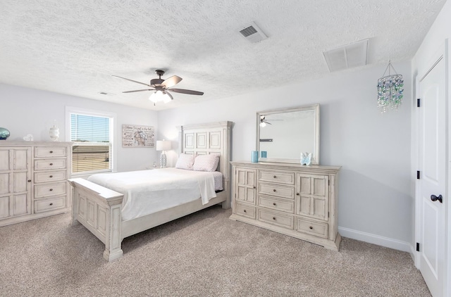 bedroom with visible vents, a textured ceiling, baseboards, light colored carpet, and ceiling fan