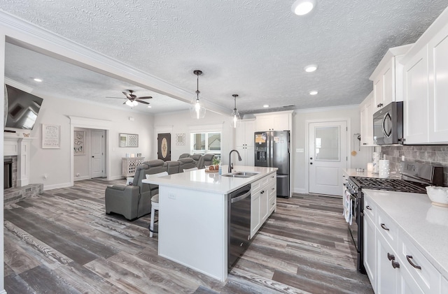 kitchen with a sink, backsplash, open floor plan, stainless steel appliances, and light countertops