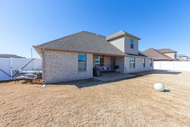 back of house with a patio area, a fenced backyard, a lawn, and brick siding