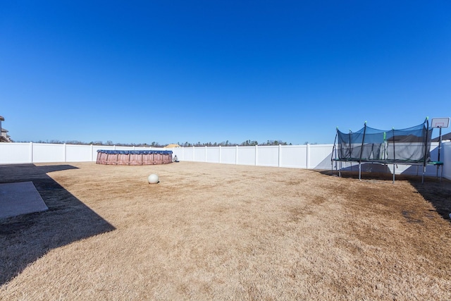 view of yard with an outdoor pool, a trampoline, and fence