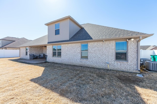 rear view of property with a patio area, roof with shingles, central AC, and fence