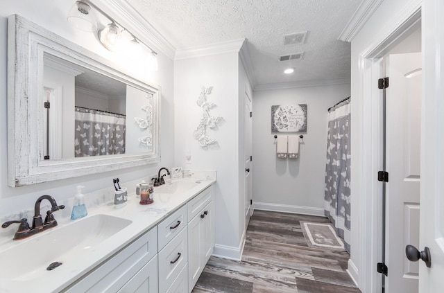 full bath featuring a sink, visible vents, a textured ceiling, and ornamental molding