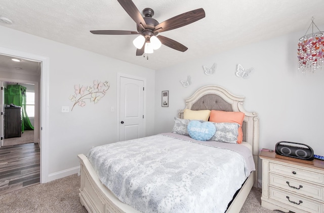 carpeted bedroom featuring a ceiling fan, baseboards, and a textured ceiling