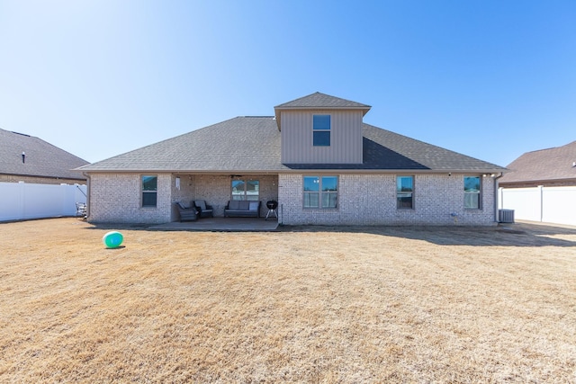 rear view of house with a patio area, a yard, brick siding, and a fenced backyard