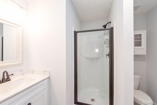 full bath with vanity, visible vents, a shower stall, a textured ceiling, and toilet
