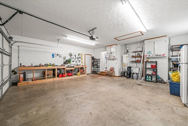 garage featuring water heater, a workshop area, a garage door opener, and freestanding refrigerator