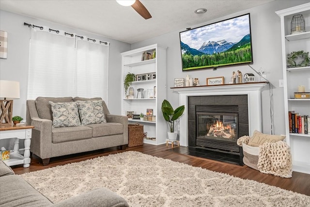 living area featuring a ceiling fan, wood finished floors, and a fireplace