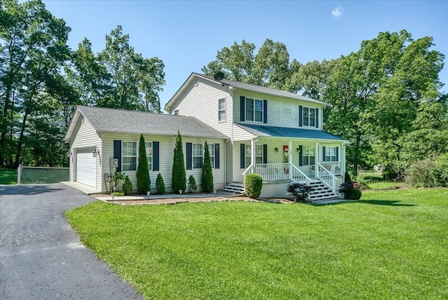 colonial house featuring a porch, a garage, a front lawn, and driveway
