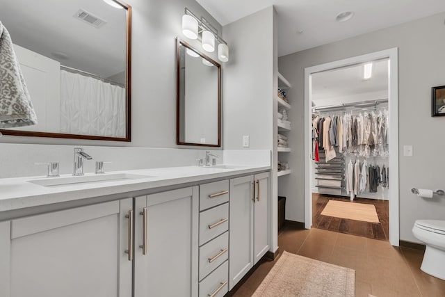 full bathroom with tile patterned flooring, visible vents, double vanity, and a sink