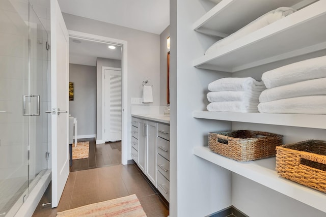 full bath featuring vanity, a shower stall, baseboards, and tile patterned flooring
