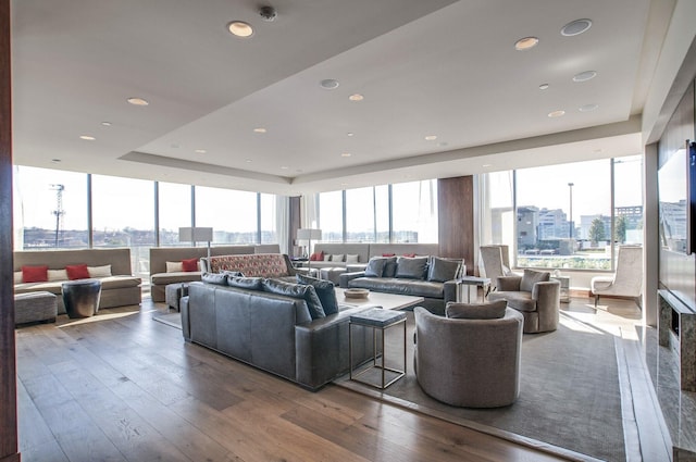 living room featuring recessed lighting, wood-type flooring, and a raised ceiling