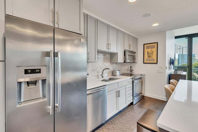 kitchen with a sink, tasteful backsplash, dark wood-style floors, stainless steel appliances, and light countertops