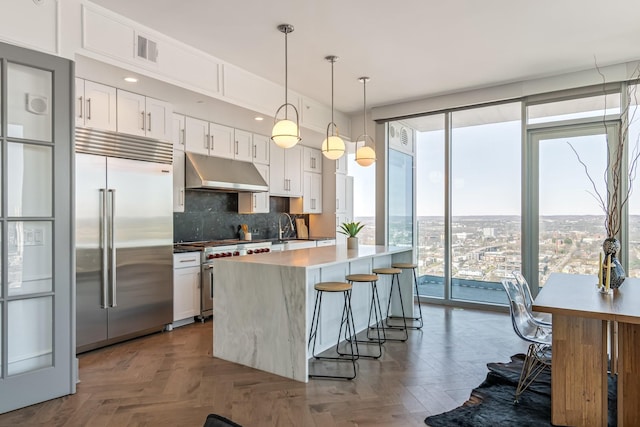 1616 W End Ave Unit 2602, Nashville, TN 37203 - kitchen with visible vents, high quality appliances, under cabinet range hood, white cabinets, and decorative backsplash