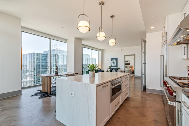 1616 W End Ave Unit 2602, Nashville, TN 37203 - kitchen with decorative light fixtures, a kitchen island, white cabinetry, stainless steel appliances, and wall chimney range hood