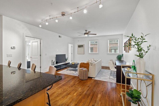 living room featuring rail lighting, visible vents, a ceiling fan, and wood finished floors