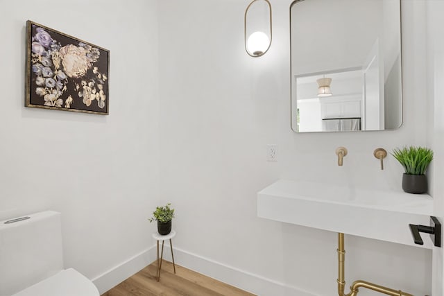 half bathroom featuring toilet, wood finished floors, and baseboards