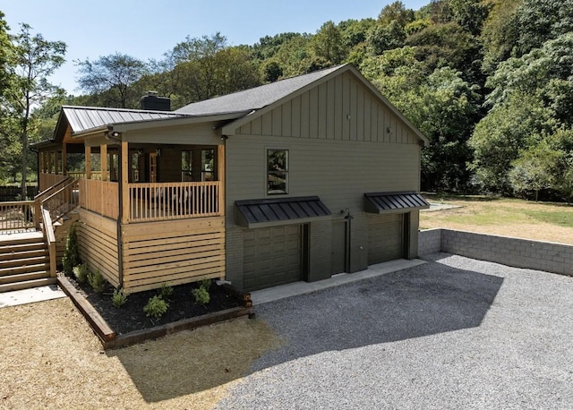 view of front facade with stairway, a chimney, a garage, board and batten siding, and metal roof