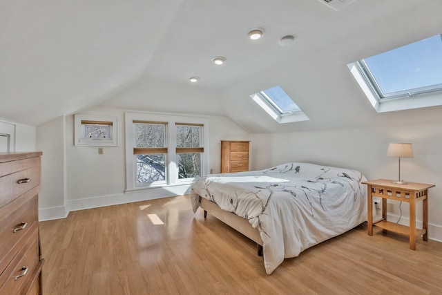 bedroom with vaulted ceiling with skylight, light wood-style floors, and baseboards