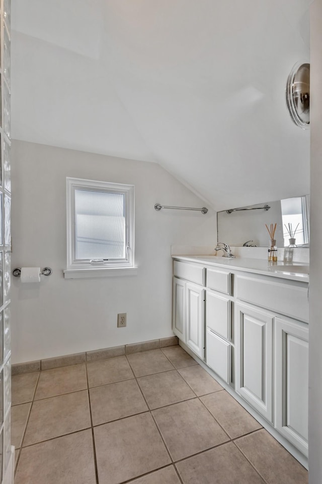bathroom featuring tile patterned floors, baseboards, vanity, and vaulted ceiling