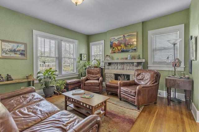 living room featuring baseboards, wood finished floors, a fireplace, and a textured wall