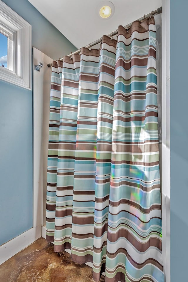 bathroom with a shower with shower curtain and concrete flooring