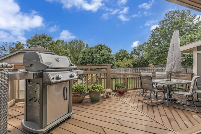 wooden terrace with outdoor dining space, a grill, and fence