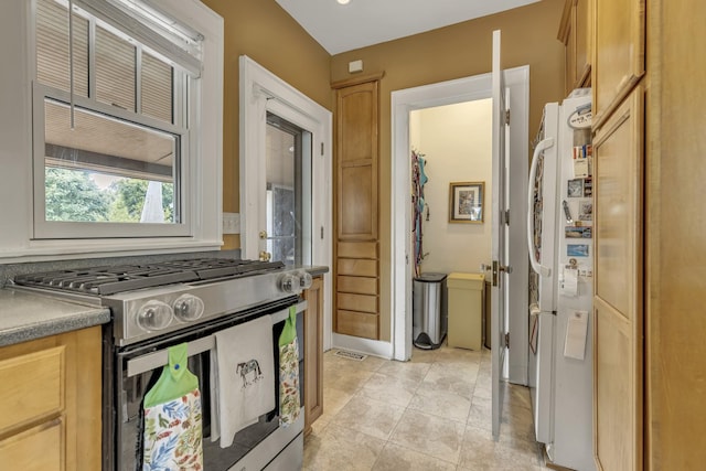 kitchen featuring light tile patterned floors, visible vents, freestanding refrigerator, and stainless steel gas range oven