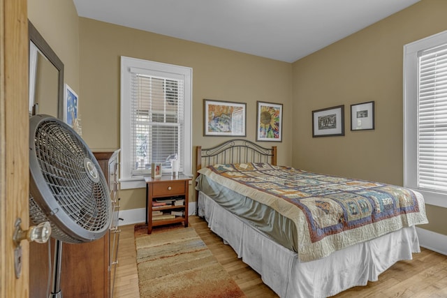 bedroom featuring baseboards, multiple windows, and light wood finished floors