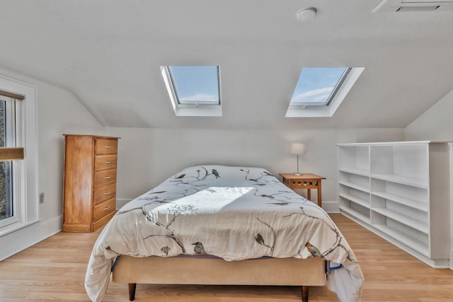 bedroom with light wood-type flooring, vaulted ceiling with skylight, baseboards, and visible vents