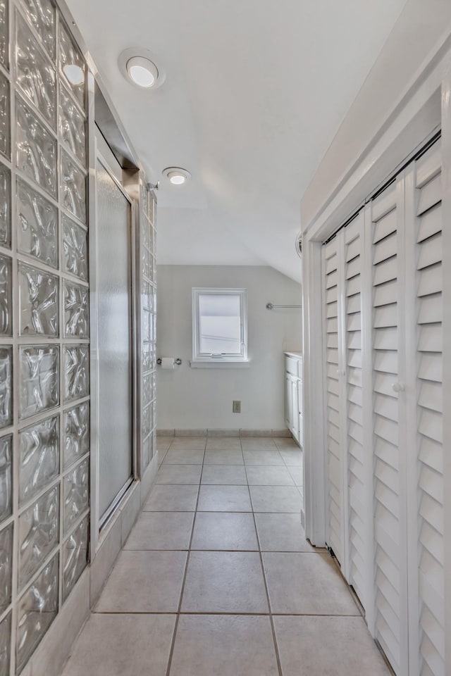 full bath featuring tile patterned floors, vaulted ceiling, and tiled shower