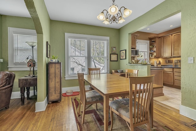 dining room with baseboards, light wood finished floors, and a chandelier