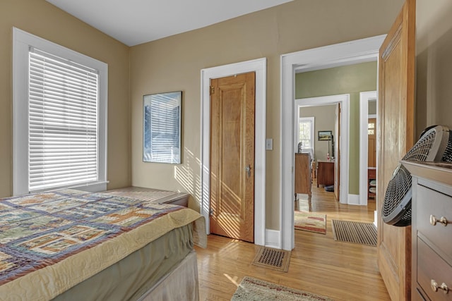 bedroom featuring visible vents, light wood-style flooring, and baseboards