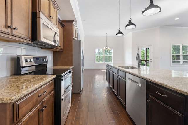 kitchen with a sink, stainless steel appliances, light stone counters, dark wood finished floors, and backsplash