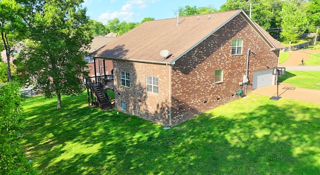 view of property exterior featuring roof with shingles, brick siding, a yard, concrete driveway, and stairway