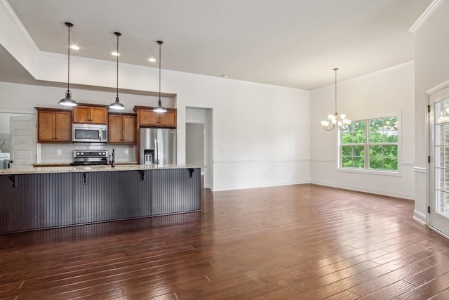 kitchen with ornamental molding, stainless steel appliances, a chandelier, and brown cabinets