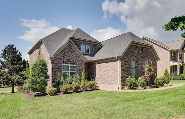 view of front of house featuring brick siding, a front lawn, and a shingled roof