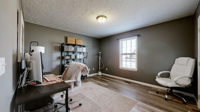 office featuring a textured ceiling, baseboards, and wood finished floors