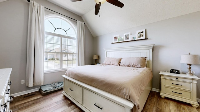 bedroom with lofted ceiling, light wood-style floors, baseboards, and a textured ceiling